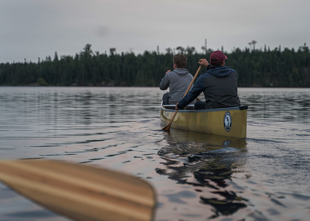 men paddling in canoe